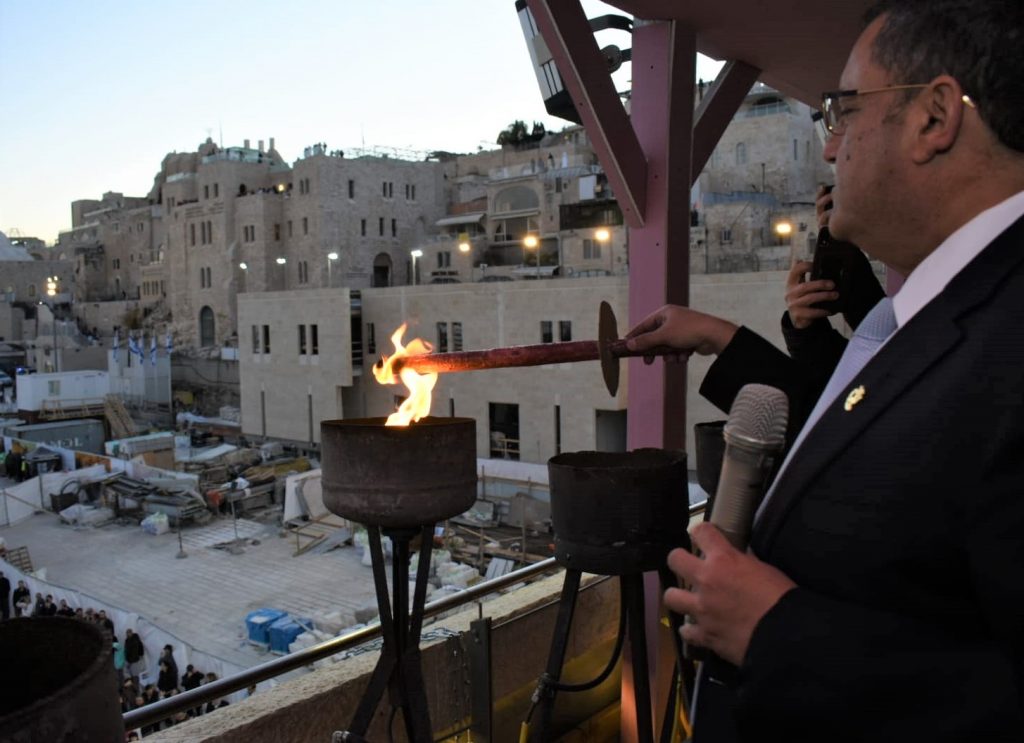 High above the Western Wall Plaza, Jerusalem Mayor Moshe Leon lights the first "candle".