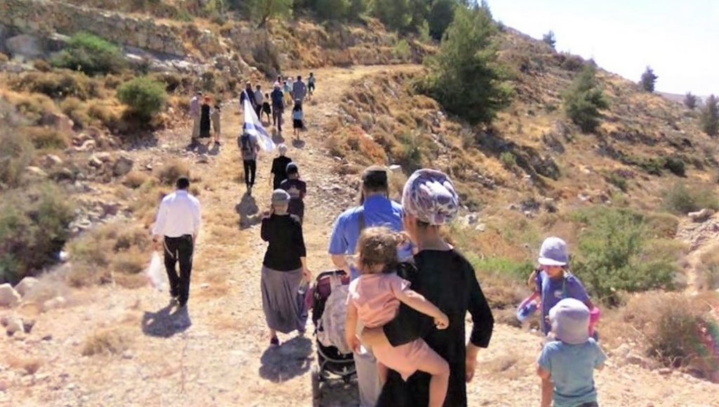 Men, women, and children walking overland to a new site.