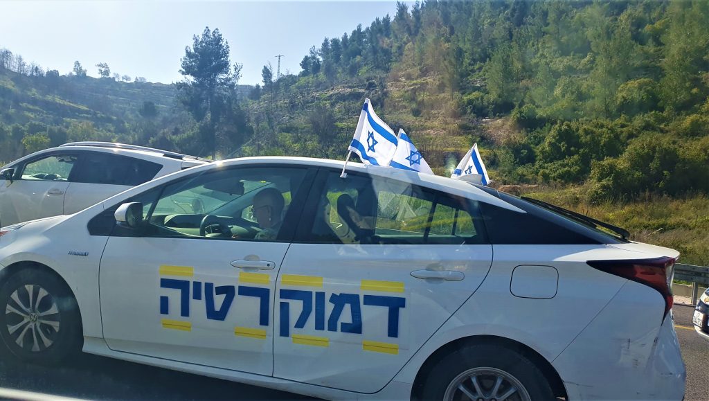 We took this photo while stuck in a massive traffic jam on Highway 1 on the way to Jerusalem. As you can see the car of the protesters is festooned with Israeli flags and the word "Democracy."