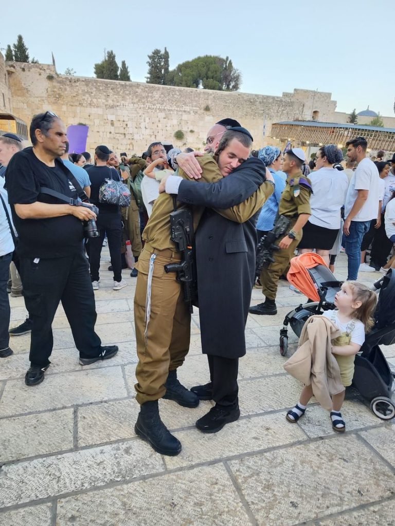 A wonderful photo at the Kotel (Western Wall) as an orthodox Jewish father hugs his son upon completion of his basic training in the IDF.